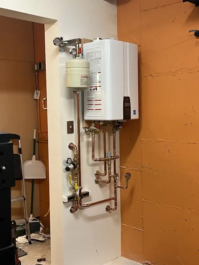 Plumbing technician inspecting water heater connections in Almont